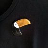 broche toucan en argile polymère aux allures graphiques présentée sur t-shirt noir