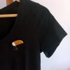 broche toucan en argile polymère aux allures graphiques présentée sur t-shirt noir